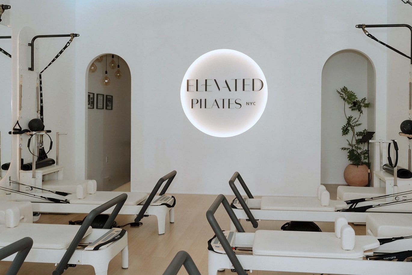 Studio interior with reformers and lit Elevated Pilates logo sign